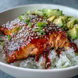 Edamame, green onions, and sesame seeds garnish this vibrant Honey Sriracha Salmon Bowl, with a drizzle of spicy sriracha mayo for extra richness.