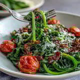 Fresh dandelion greens salad with lemon vinaigrette and Parmesan cheese, topped with cherry tomatoes and pine nuts.  