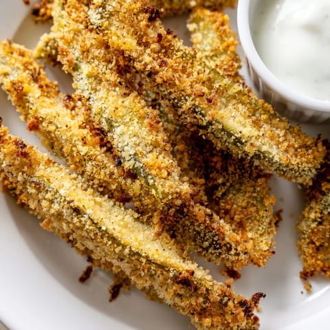 Steam rises from freshly fried pickles, with a side of ranch dressing for dipping, ready to serve. 