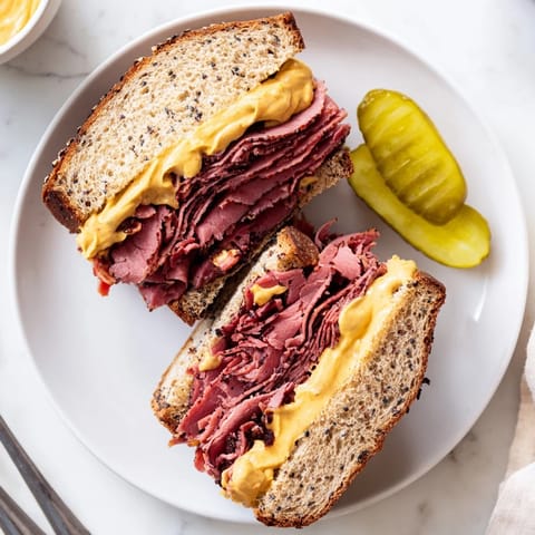 A classic Pastrami on Rye sandwich, served with a crunchy dill pickle spear.
