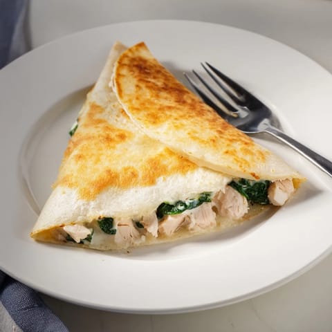 Golden, crispy Chicken and Spinach Quesadilla wedges with melted mozzarella and tender spinach on a white plate, ready to serve.  