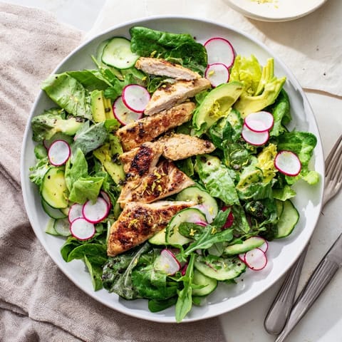 A vibrant bowl of Spring Detox Chicken Salad with grilled chicken slices, crisp cucumber, peppery radish, and mixed greens, all tossed in a zesty lemon vinaigrette.