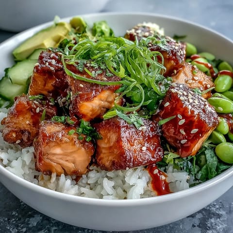 Flaky marinated salmon cubes and creamy avocado sit atop fluffy jasmine rice in this vibrant Salmon Rice Bowl, drizzled with spicy sriracha mayo.