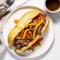 A steaming Italian Beef Sandwich piled high with juicy shredded beef and spicy giardiniera on a toasted hoagie roll.
