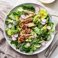 A vibrant bowl of Spring Detox Chicken Salad with grilled chicken slices, crisp cucumber, peppery radish, and mixed greens, all tossed in a zesty lemon vinaigrette.