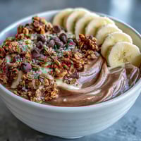 Creamy Chunky Monkey Smoothie Bowls topped with banana slices, crunchy granola, and hemp seeds for breakfast.