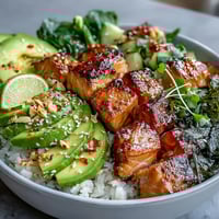 Avocado Salmon Bowl with marinated salmon, creamy avocado, spicy chili oil, and chopped peanuts on seasoned sushi rice.