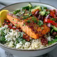 Pan-seared Mediterranean Salmon Bowl with crispy rice, vibrant bell peppers, sun-dried tomatoes, and creamy feta.