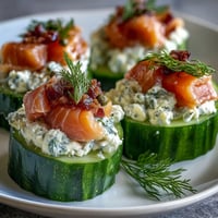 Cucumber bites topped with cream cheese and smoked salmon, garnished with dill and capers for a fresh, elegant appetizer.